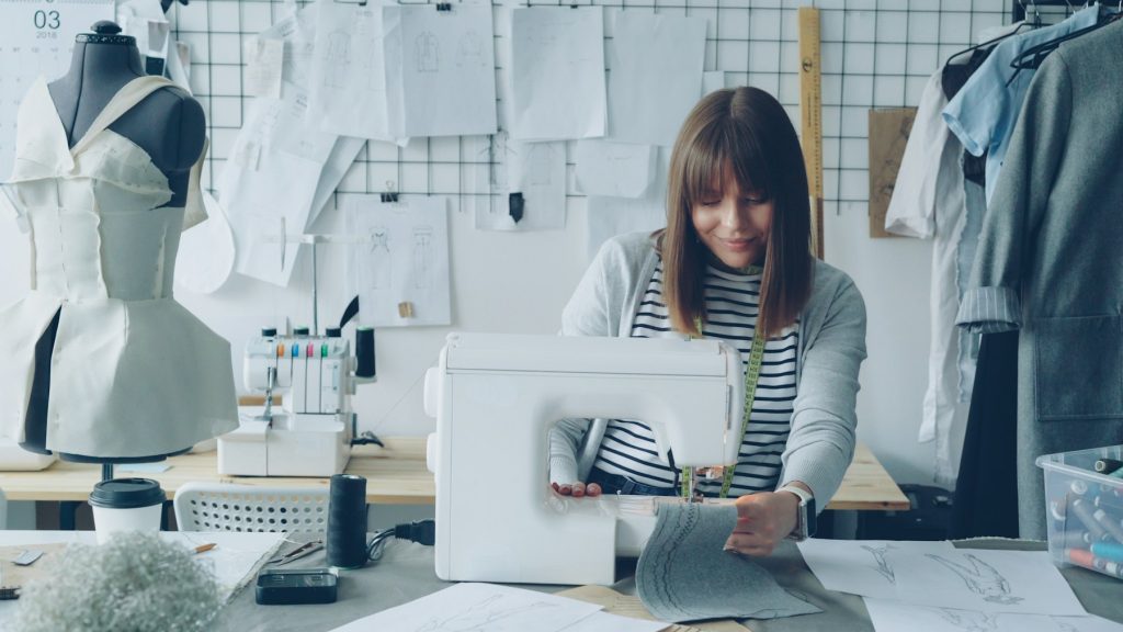 Bancada de costura com ferramentas, materiais e itens de produção organizados
