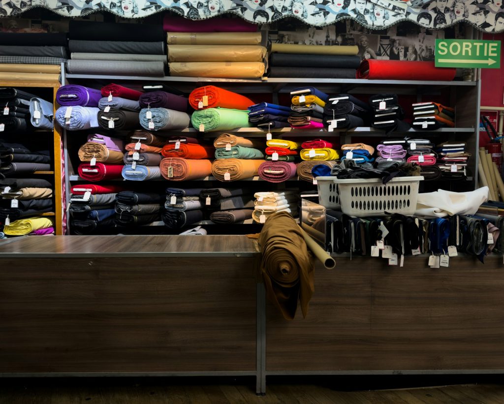 Rolos de tecidos coloridos organizados em prateleiras de loja